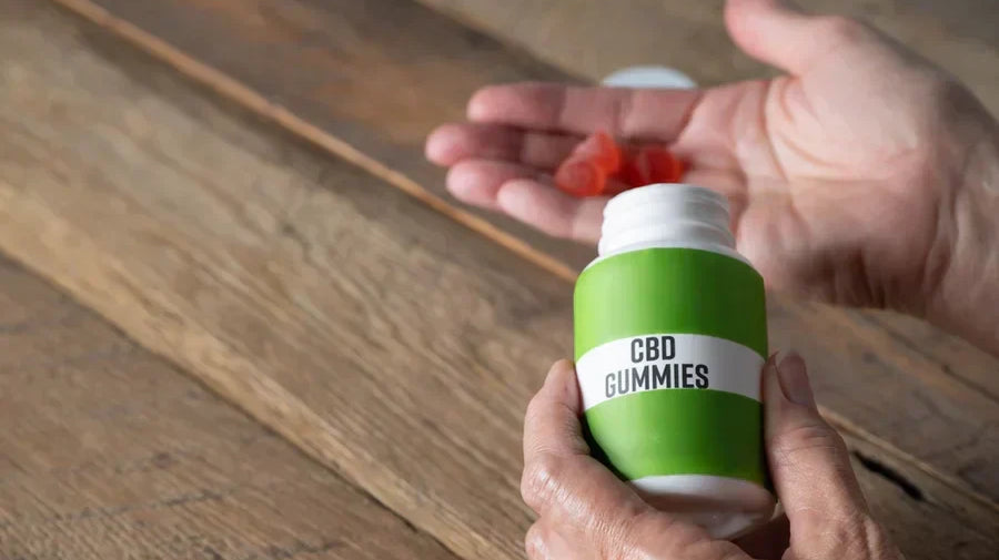 Older hands hold orange CBD gummies against a wooden background for a Wana fast asleep vs. Stay asleep gummies Goldfish Distro. article.