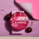 Camino Wild Cherry Excite gummies featuring 5mg THC per gummy, packaged in a vibrant round container on a textured surface.
