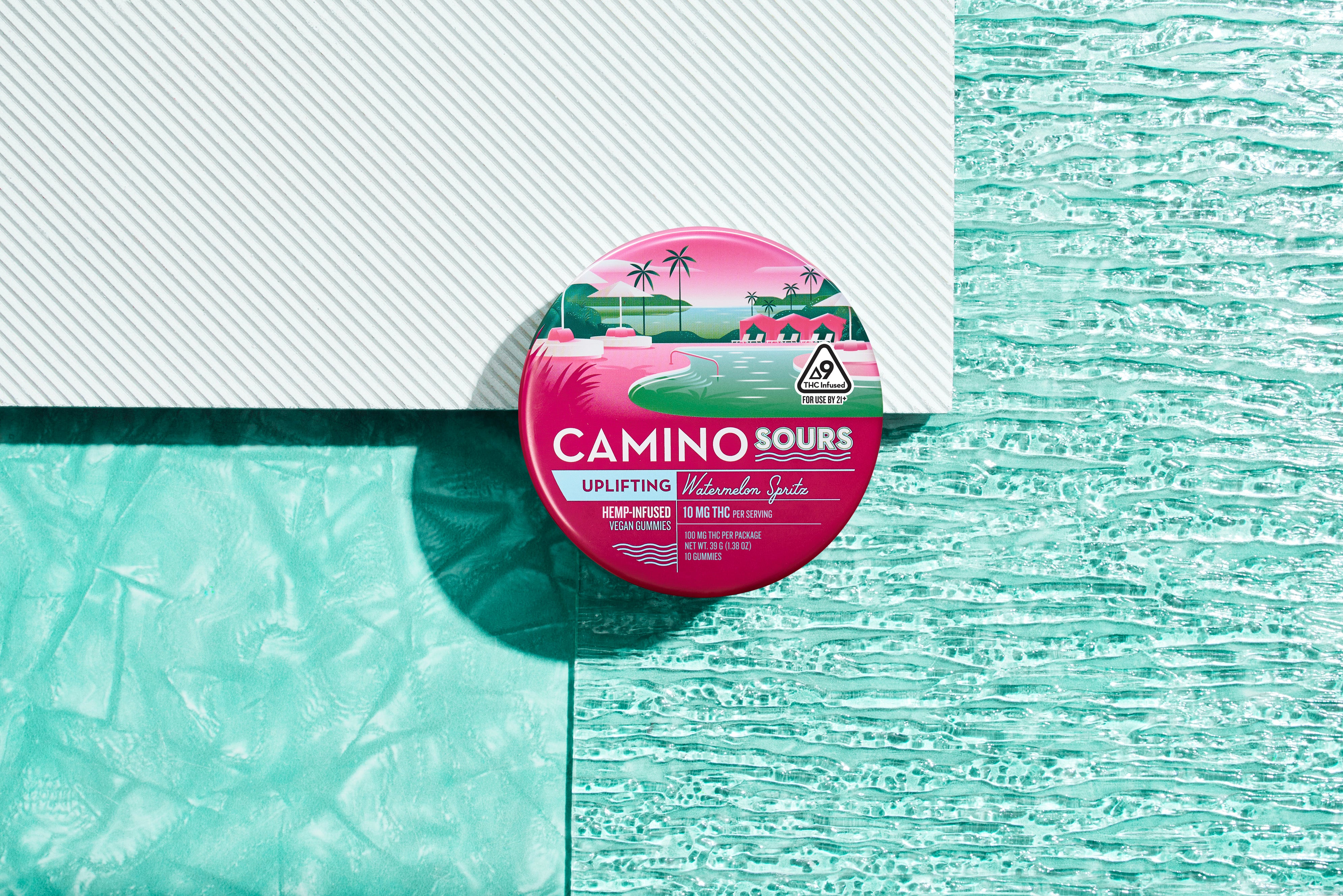 Pink and green watermelon spritz flavored hemp-infused gummies in a round container with tropical ocean and palm tree desi...