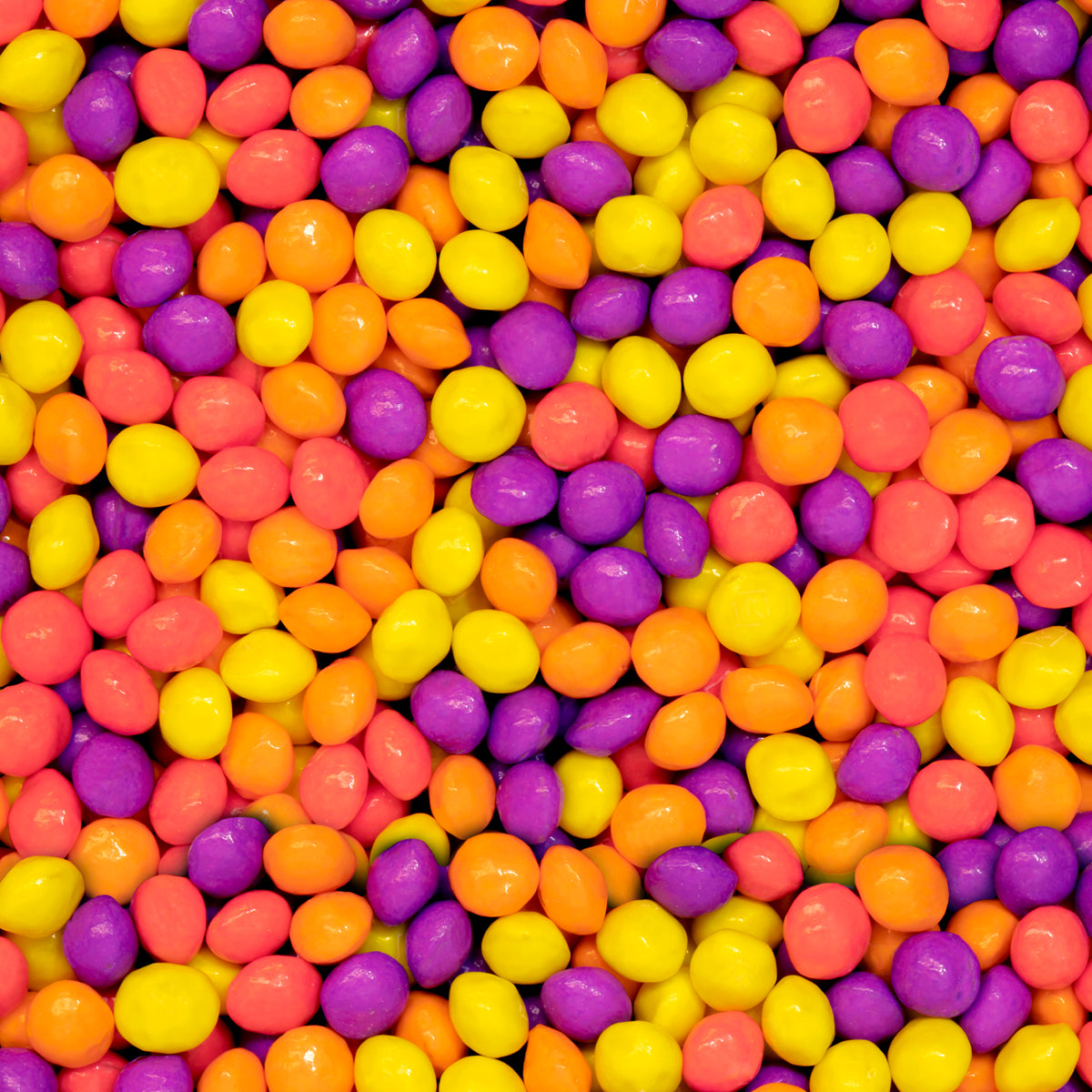 Colorful assortment of Joy Bombs Tropical Haze hemp chews in vibrant shades of purple, orange, and yellow.