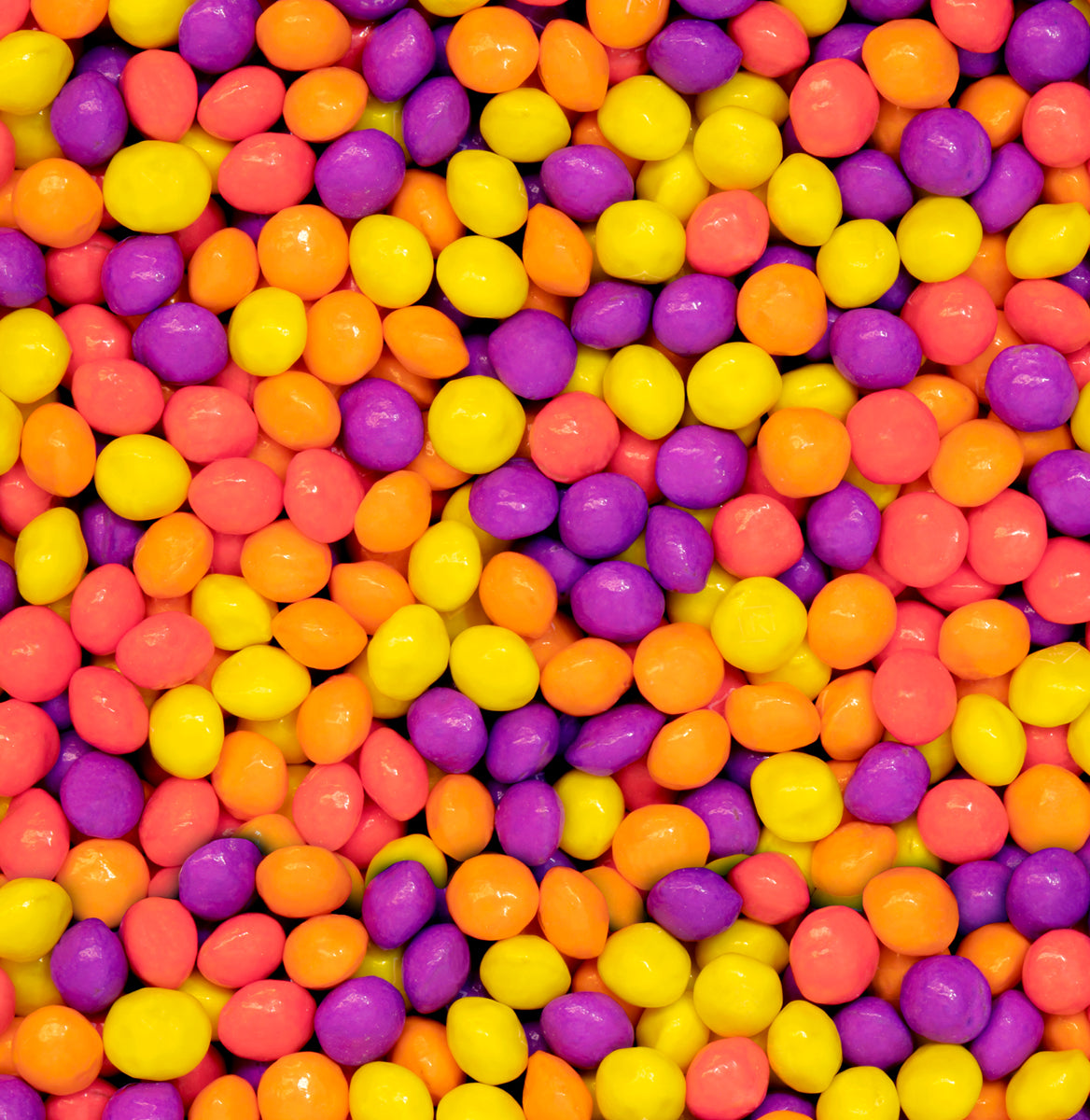 Colorful assortment of Joy Bombs Tropical Haze hemp chews in vibrant purple, yellow, and orange, showcasing their fun appearance.