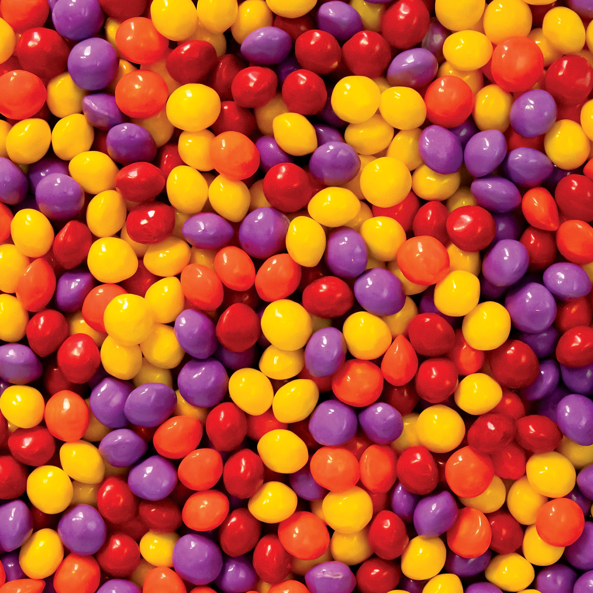 Colorful assortment of small, round fruit-flavored chews, featuring vibrant red, yellow, purple, and orange hues.
